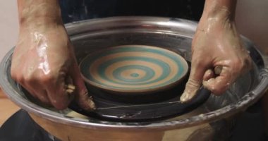 Potter fırlatma çarkından kil kasesini kesiyor, yakın plan. Seramik sanat