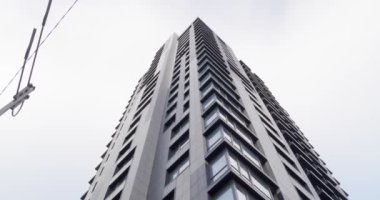 Bulutlu gökyüzüne karşı gökdelen, alçak açı. Kamera sağa dönüyor.