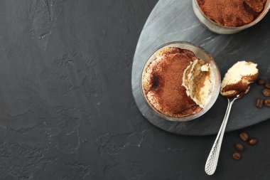 Bardakta nefis tiramisu, siyah masada kaşık ve kahve çekirdekleri, üst manzara. Metin için boşluk