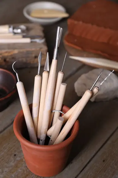 Set of different clay crafting tools on wooden table in workshop