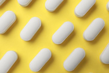 Sarı arka planda vitamin hapları, düz uzanma