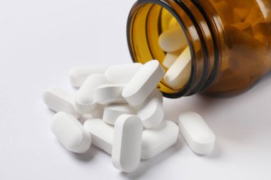Beyaz arkaplanda şişe ve vitamin kapsülleri, yakın plan