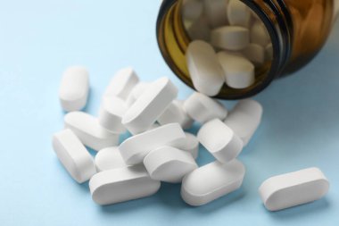 Açık mavi arka planda şişe ve vitamin kapsülleri, yakın plan