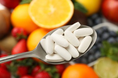 Kaşık içinde vitamin hapları taze meyvelerin üstünde, yakın plan.