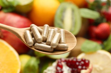 Kaşık içinde vitamin hapları taze meyvelere karşı, yakın plan.