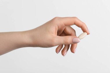 Beyaz arka planda vitamin hapı tutan kadın, yakın plan. Sağlık takviyesi