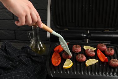 Gri masadaki ızgarada limonlu dolma biberli köfte pişiren kadın, yakın plan.