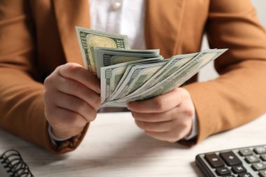 Para değişimi. Beyaz ahşap masada elinde dolar banknotları tutan kadın.