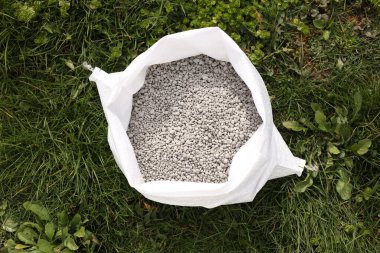 Fertilizer in bag on green grass outdoors, top view clipart