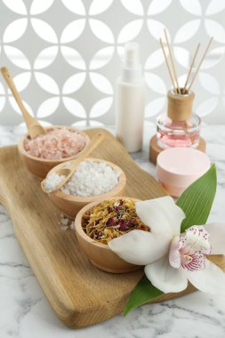 Farklı spa ürünleri ve beyaz mermer masa üzerinde orkide ile güzel bir kompozisyon.