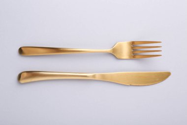 Gri masadaki şık çatal bıçak takımı, üst manzara.