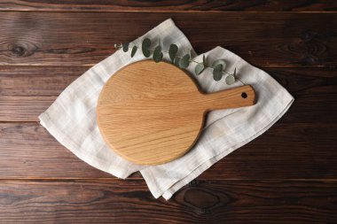 Kesme tahtası, okaliptüs dalı ve tahta masa üzerindeki peçete.