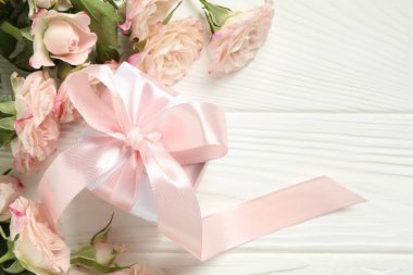Anneler Günün kutlu olsun. Güzel güller ve hediye kutusu beyaz ahşap masa üzerinde, düz yatıyordu. Metin için boşluk
