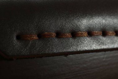 Arka planda kahverengi dikişli koyu deri, yakın plan.