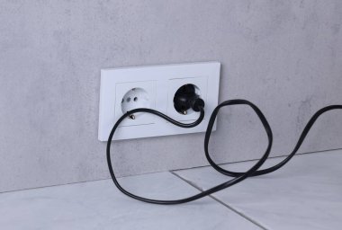 Gri duvarda elektrik prizi ve prizler var.