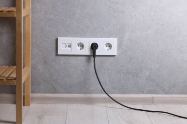 Gri duvarda elektrik prizi ve prizler var.