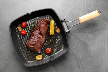 Lezzetli ızgara et ve sebzeler tavada gri masada.