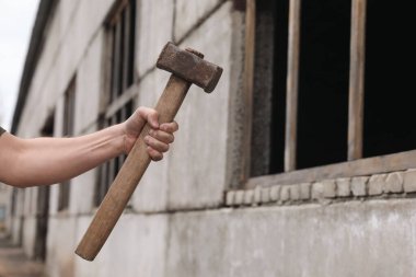 Dışarıdaki eski binanın yakınında balyozlu bir adam var. Metin için boşluk