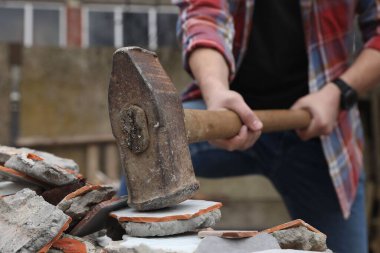 Balyozla tuğla kıran bir adam açık havada, seçici bir odak