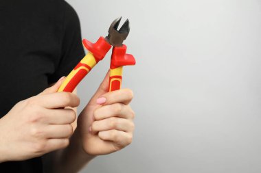 Gri arka planda çapraz pense olan kadın, yakın plan. Metin için boşluk