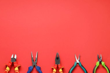 Kırmızı arka planda farklı pense, düz yatış. Metin için boşluk