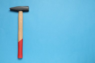 Açık mavi arka planda ahşap saplı yeni çekiç, üst manzara. Metin için boşluk