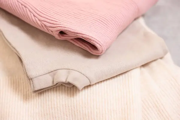 Stack of folded clothes on grey table, closeup