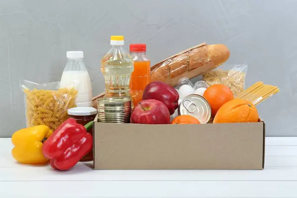 Humanitaire Hulp Verschillende Voedingsmiddelen Voor Donatie Doos Witte Houten Tafel — Stockfoto