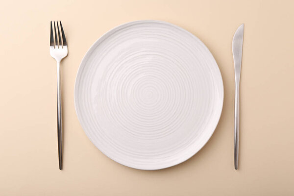 Setting with stylish cutlery on beige table, top view