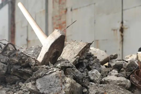 Sledgehammer on pile of broken stones outdoors, closeup