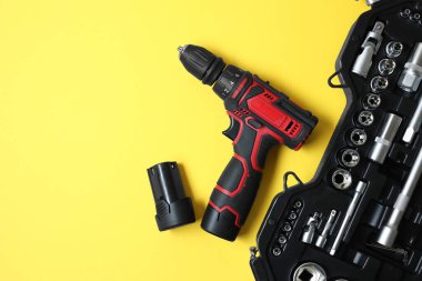 Elektrikli tornavida ve sarı arka planda parçaları olan düz bir çanta. Metin için boşluk