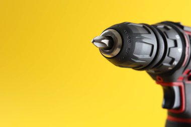 Sarı arka planda modern elektrikli tornavida, yakın plan. Metin için boşluk