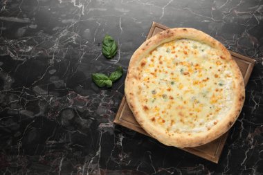 Lezzetli peynirli pizza ve fesleğen siyah mermer masa, düz. Metin için boşluk