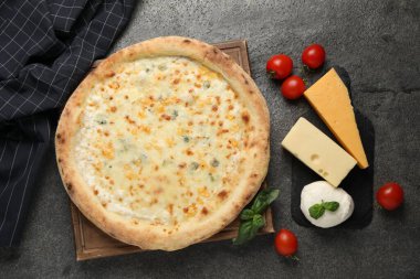 Lezzetli peynirli pizza ve malzemeler koyu gri masada, düz yatıyordu.
