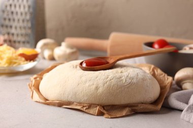 Pizza hamuru ve ürünler gri desenli masa üzerinde, yakın plan.