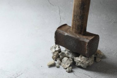 Gri arka planda bir balyoz ve kırık taş parçaları, yakın plan. Metin için boşluk