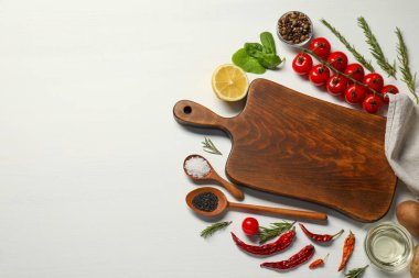 Yemek pişiriyorum. Kesme tahtası ve beyaz ahşap masa üzerindeki farklı ürünler. Metin için boşluk