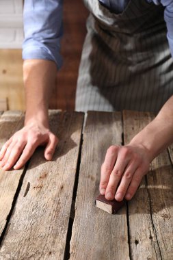 Zımpara kağıdıyla ahşap masayı cilalayan adam, yakın plan.