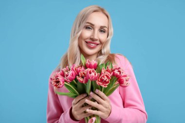 Açık mavi arka planda güzel genç kadın