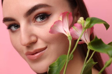 Sahte çilleri ve pembe arka planda çiçekleri olan güzel bir kadın. Yakın plan.