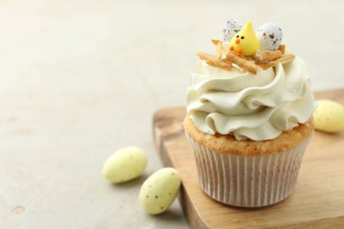 Lezzetli paskalya keki, vanilya kremalı ve gri masada şekerler, mesaj için yer var.