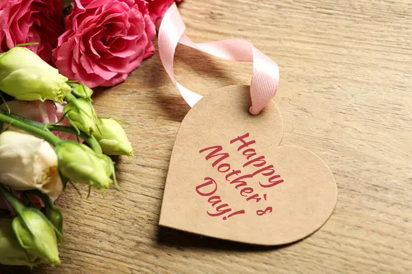 Happy Mother\'s Day. Heart shaped greeting label and beautiful flowers on wooden table