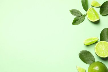 Açık yeşil zemin üzerinde yaprakları olan taze, olgun limonlar.