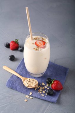 Bardakta lezzetli yoğurt, gri masada yulaf ve böğürtlen