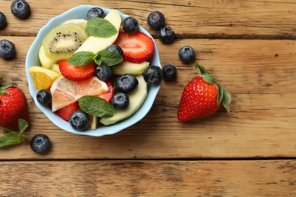 ボウルで美味しいフルーツサラダと木のテーブルの食材 フラットレイ — ストック写真