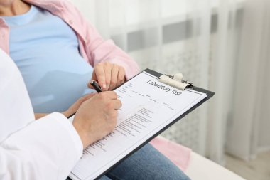 Klinikteki hamile hastaya laboratuvar testinin sonuçlarını içeren bir doktor, yakın plan.