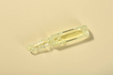 Bej arka planda sıvı bulunan cam ampul, üst görünüm