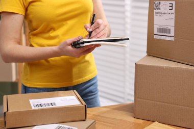 Paketleme. Postane çalışanı içeride notlar yazıyor, kapatıyor.