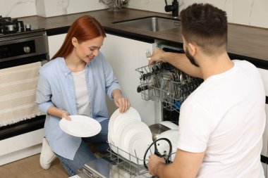 Güzel bir çift bulaşık makinesini tabakla dolduruyor.