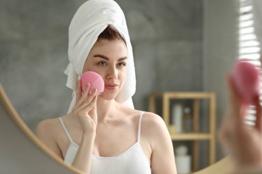 Yüzünü yıka. Banyoda aynanın yanında fırçası olan genç bir kadın.